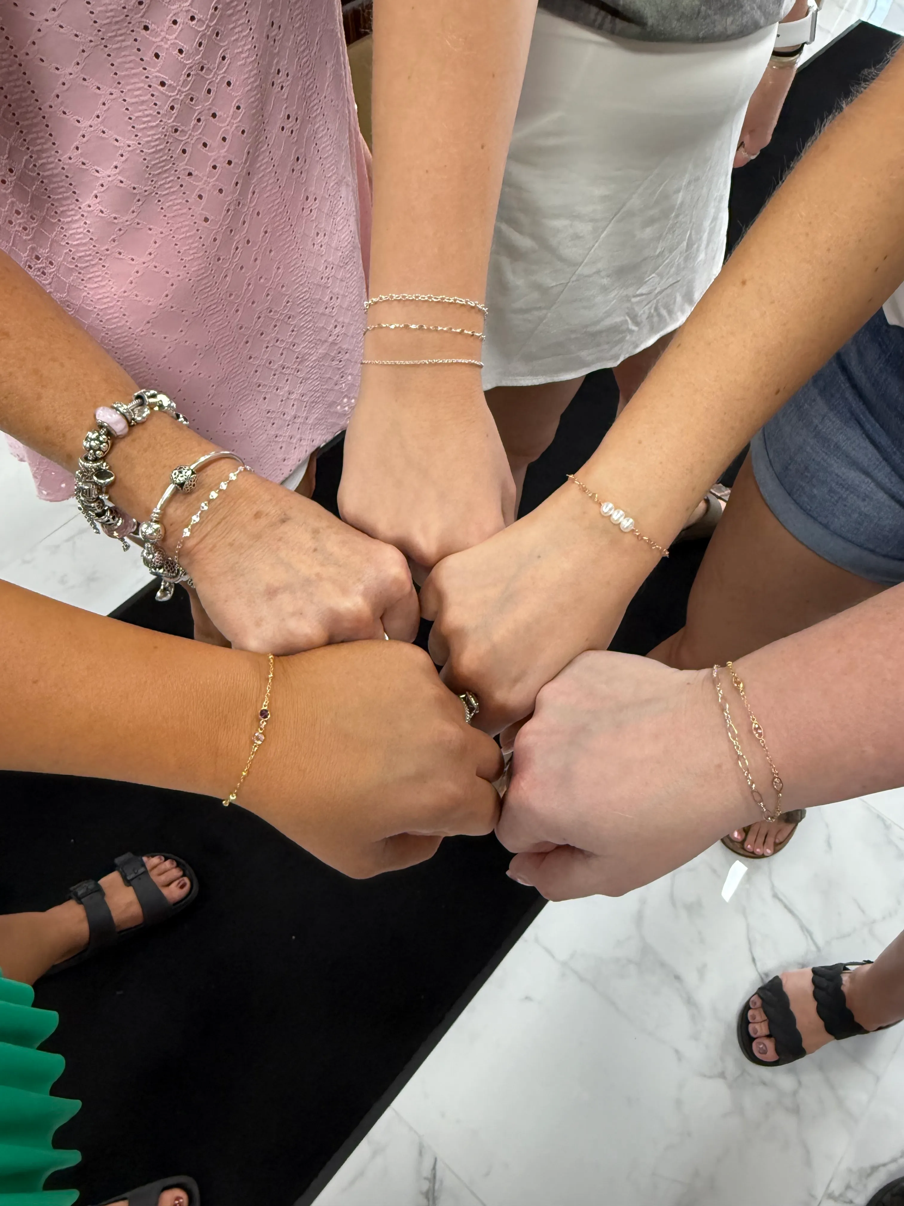 Five friends showing matching bracelets at a bridal event